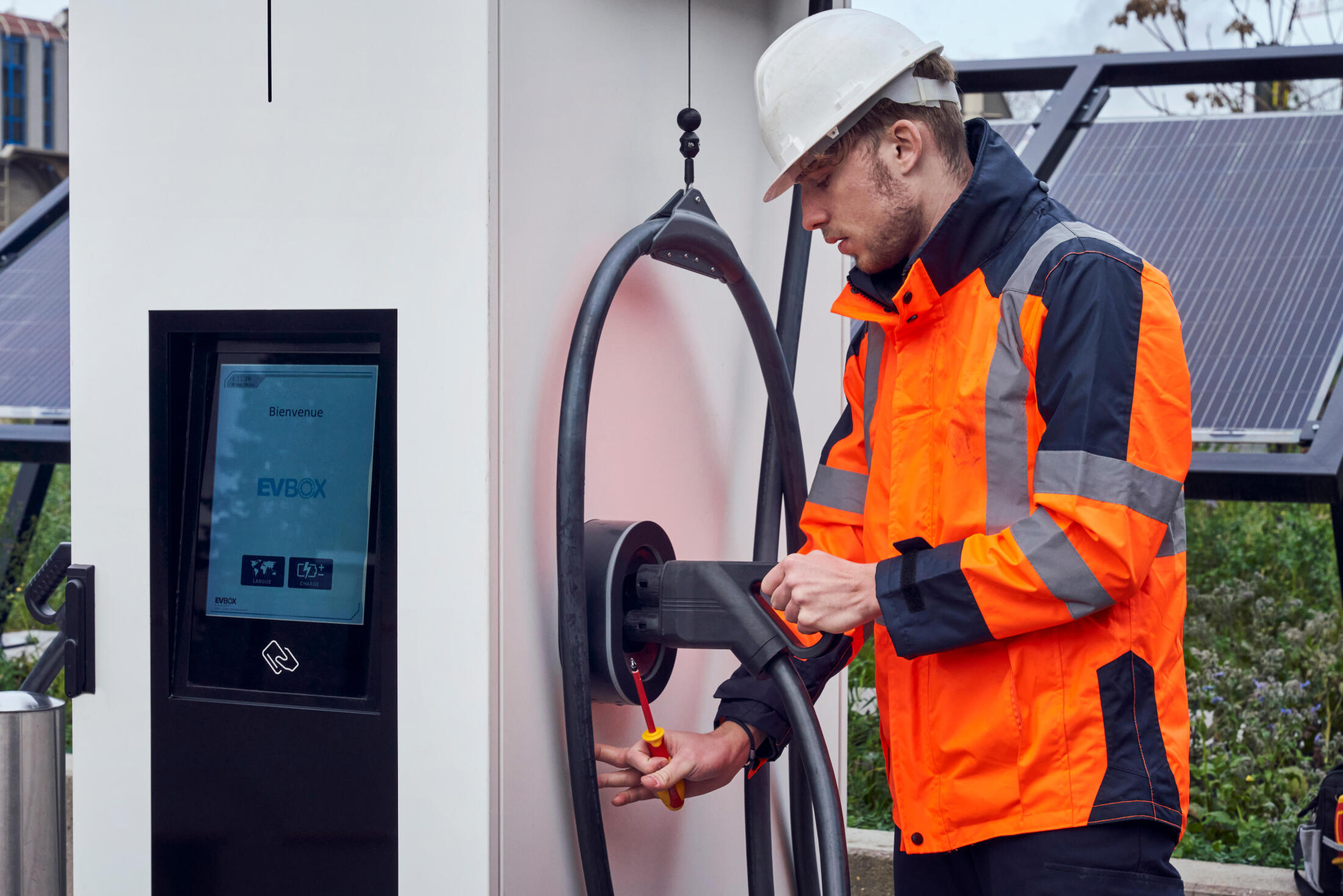 Roue de la décarbonation - étape 4 (nous pilotons la mise en œuvre et soutenons vos opérations) : un électricien intervient chez un client, à bord de son Renault Trucks E-Tech Trafic, pour la mise en marche de la borne de recharge